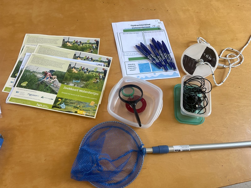papieren opdrachten, visnet, bakje en ander gereedschap om water te onderzoeken