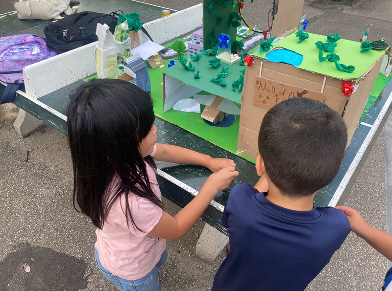 kinderen bouwen van karton en andere materialen een gebouw in hun wijk van de toekomst