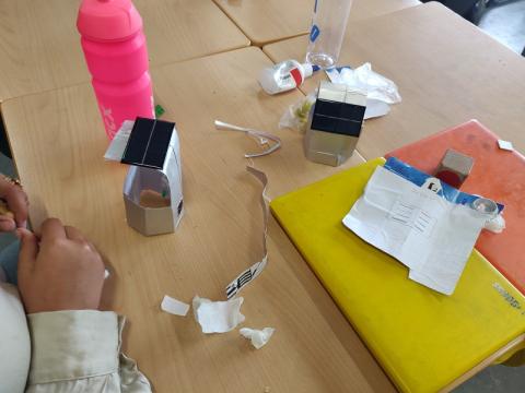 leerling bouwt huisje van sappak met zonnepaneeltje op het dak